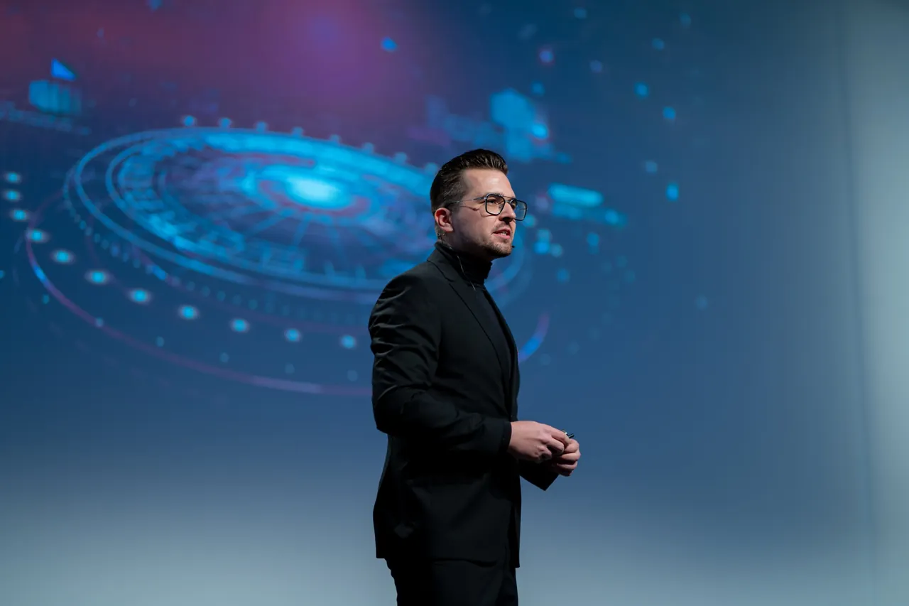 Frederik Neust im schwarzen Anzug mit Rollkragen bei seiner KI-Keynote auf dem Aufstiegskongress 2023