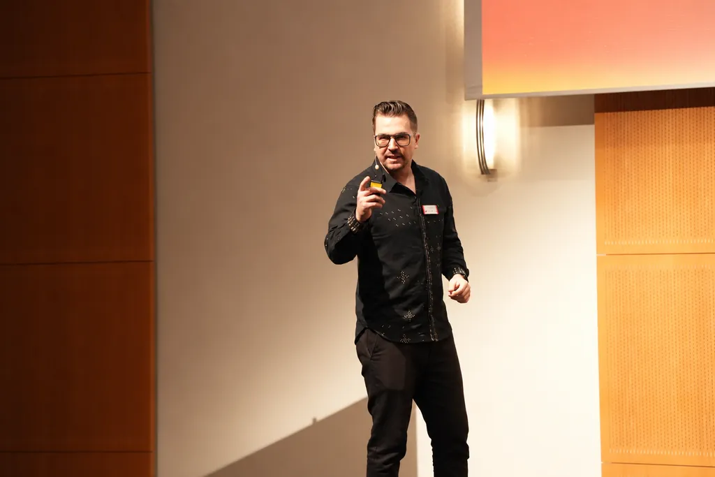 Keynote-Speaker Frederik Neust zeigt beim FIBO Congress 2023 mit dem Presenter ins Publikum