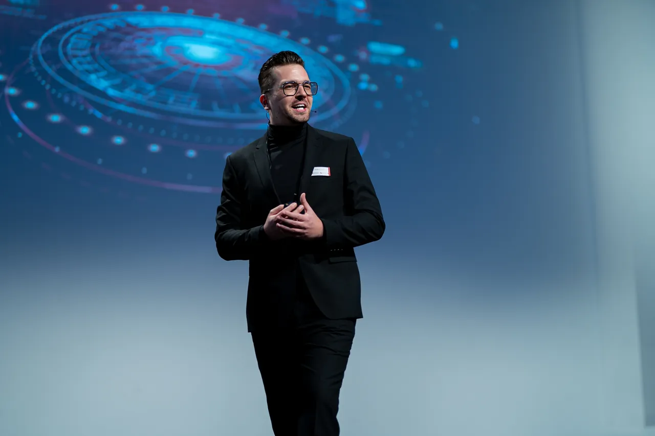 KI-Keynote von SEO- und GEO-Speaker Frederik Neust auf dem Aufstiegskongress 2023, im Hintergrund eine blaue Projektion
